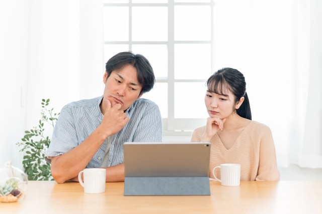 パソコンを見て悩むカップル